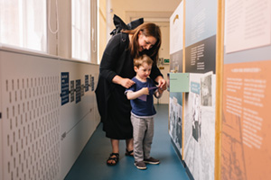 you,g boy and mother looking at pen museum display